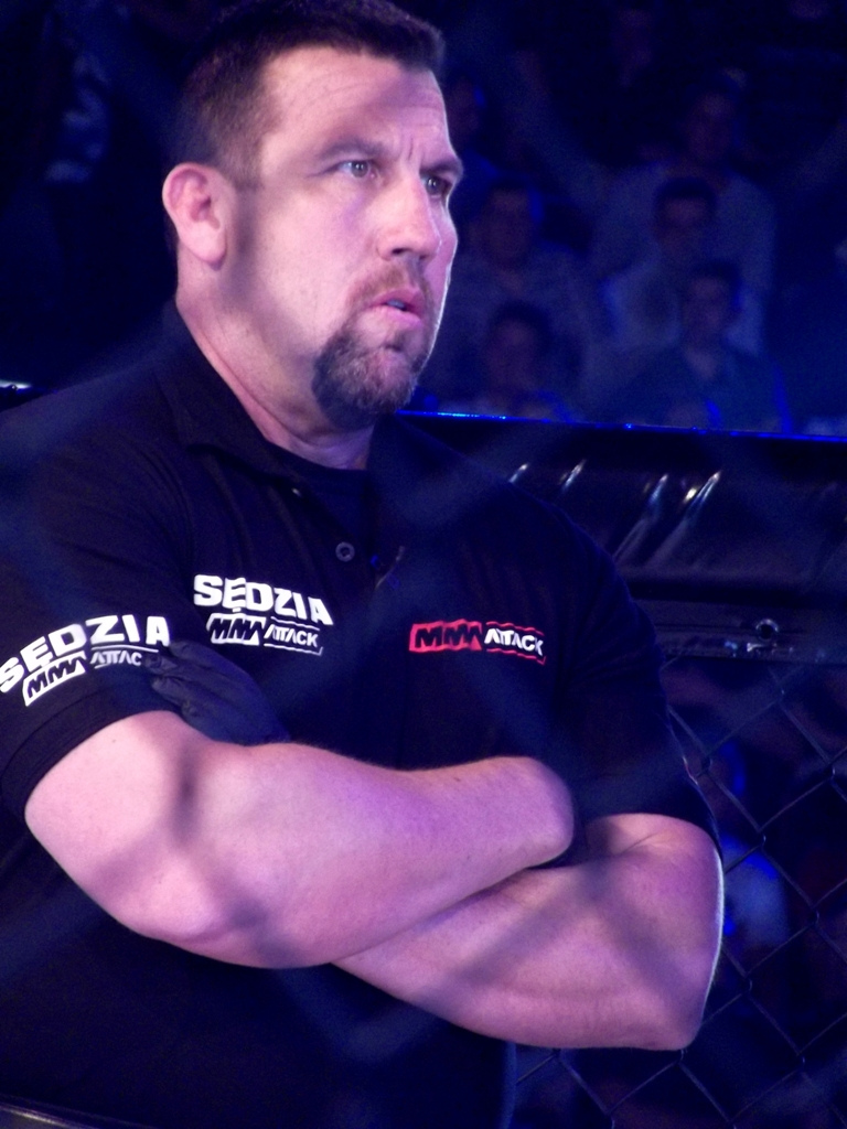 MMA official John McCarthy seated with his arms folded in 2012.